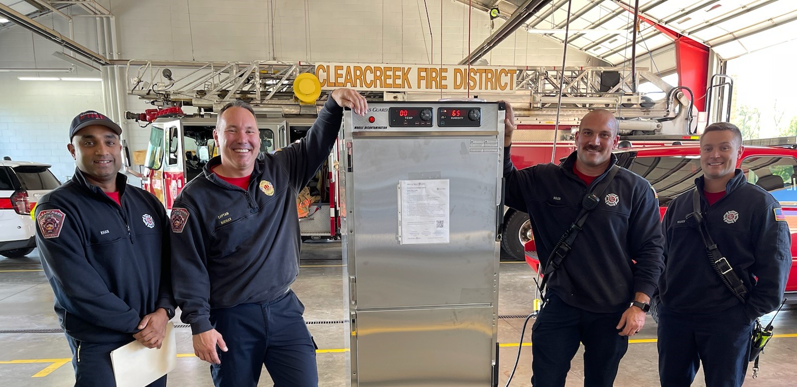 Clearcreek Fire Department firefighters pose next to Cres Guard mobile decontamination cabinet